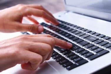 get paid to type Hands typing on a laptop computer keyboard.