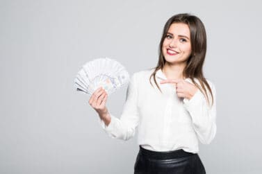 how to make an extra $1000 a month money woman Image of happy young woman standing isolated over white background. Looking camera holding money pointing.